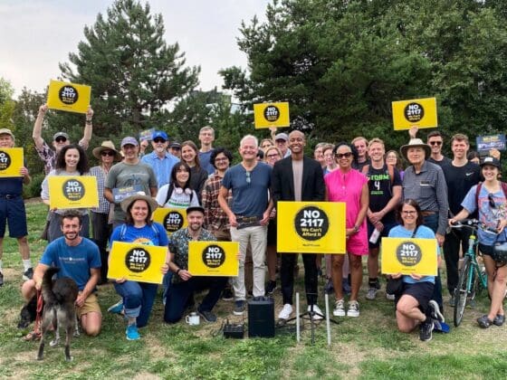 Volunteers gather holding No on 2117 signs.