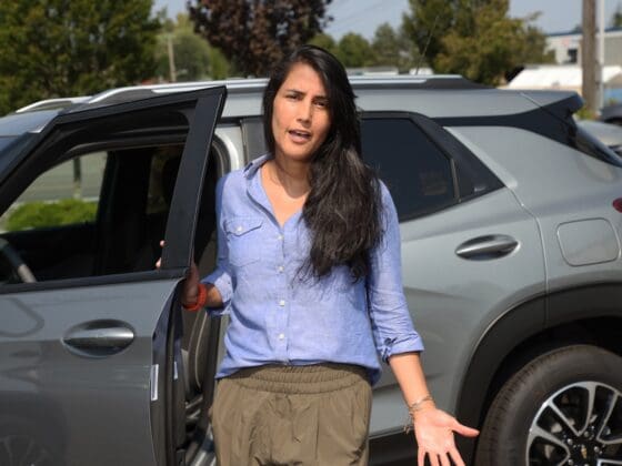 A woman standing outside her car and talking.