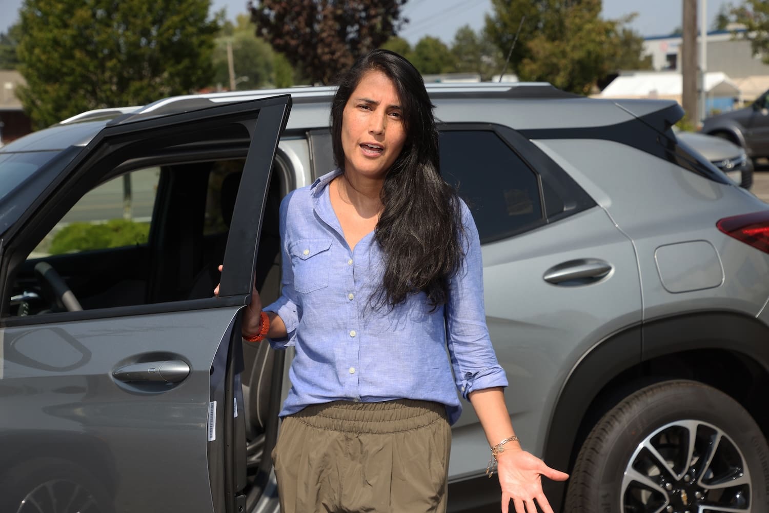 A woman standing outside her car and talking.